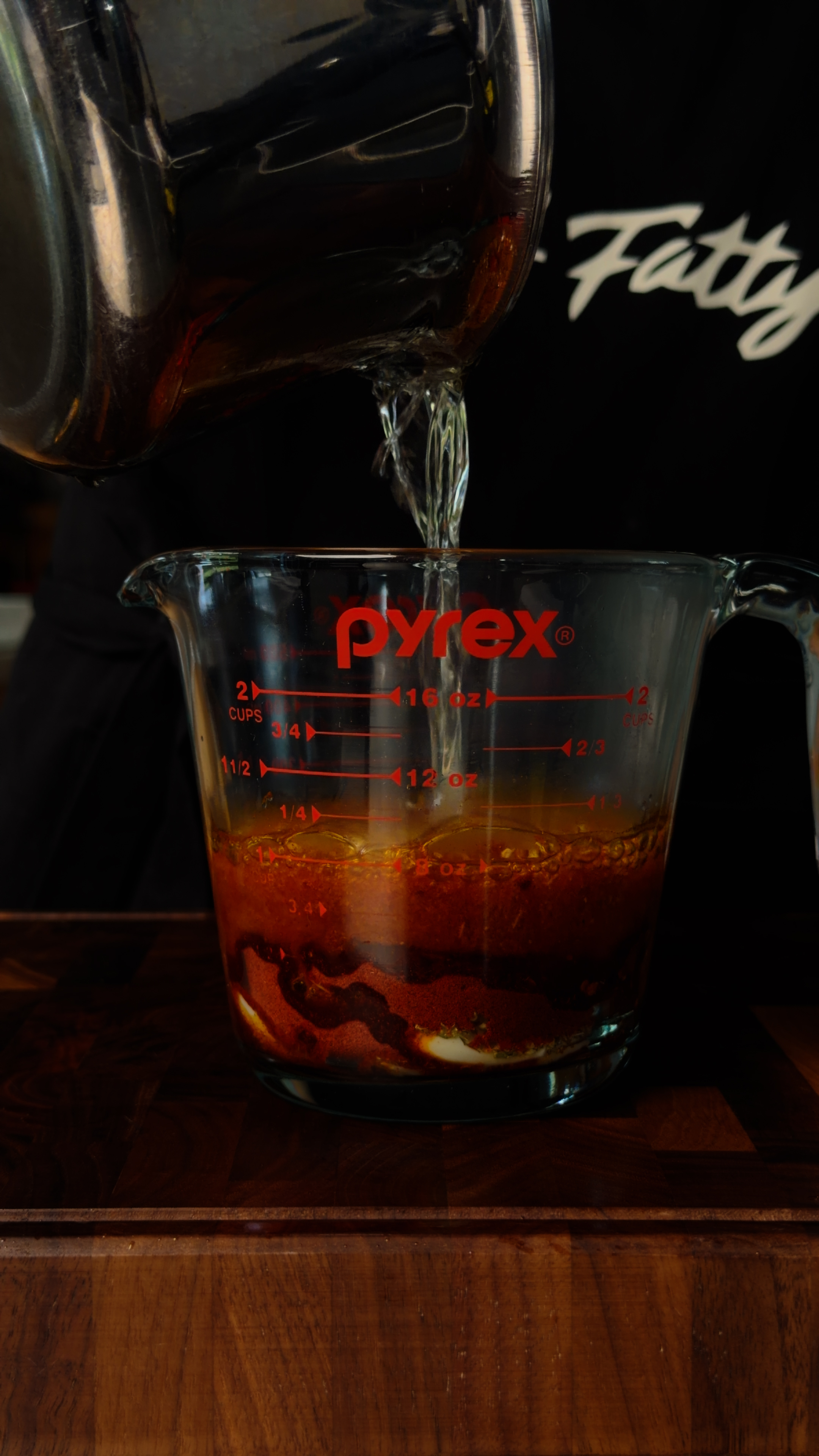 Hot oil blooming into vivid ruby red as it hits smoked paprika in a Pyrex measuring cup