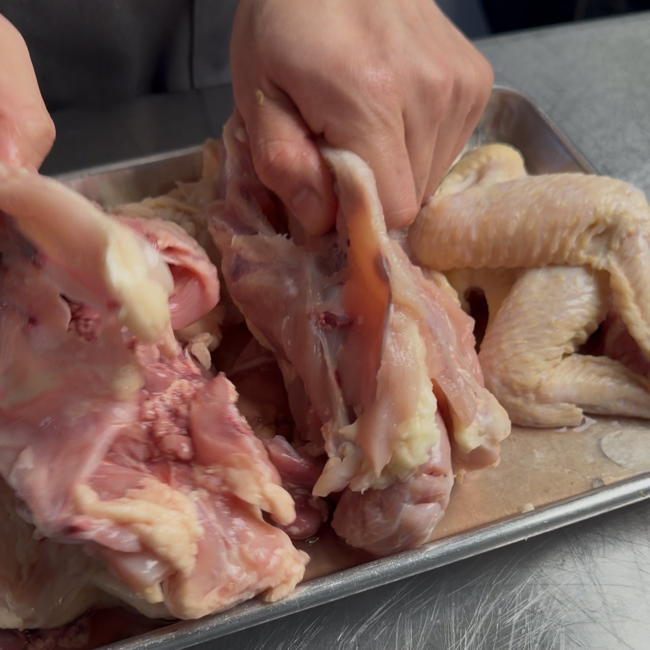 Two raw chicken carcasses on a sheet tray ready for the stockpot