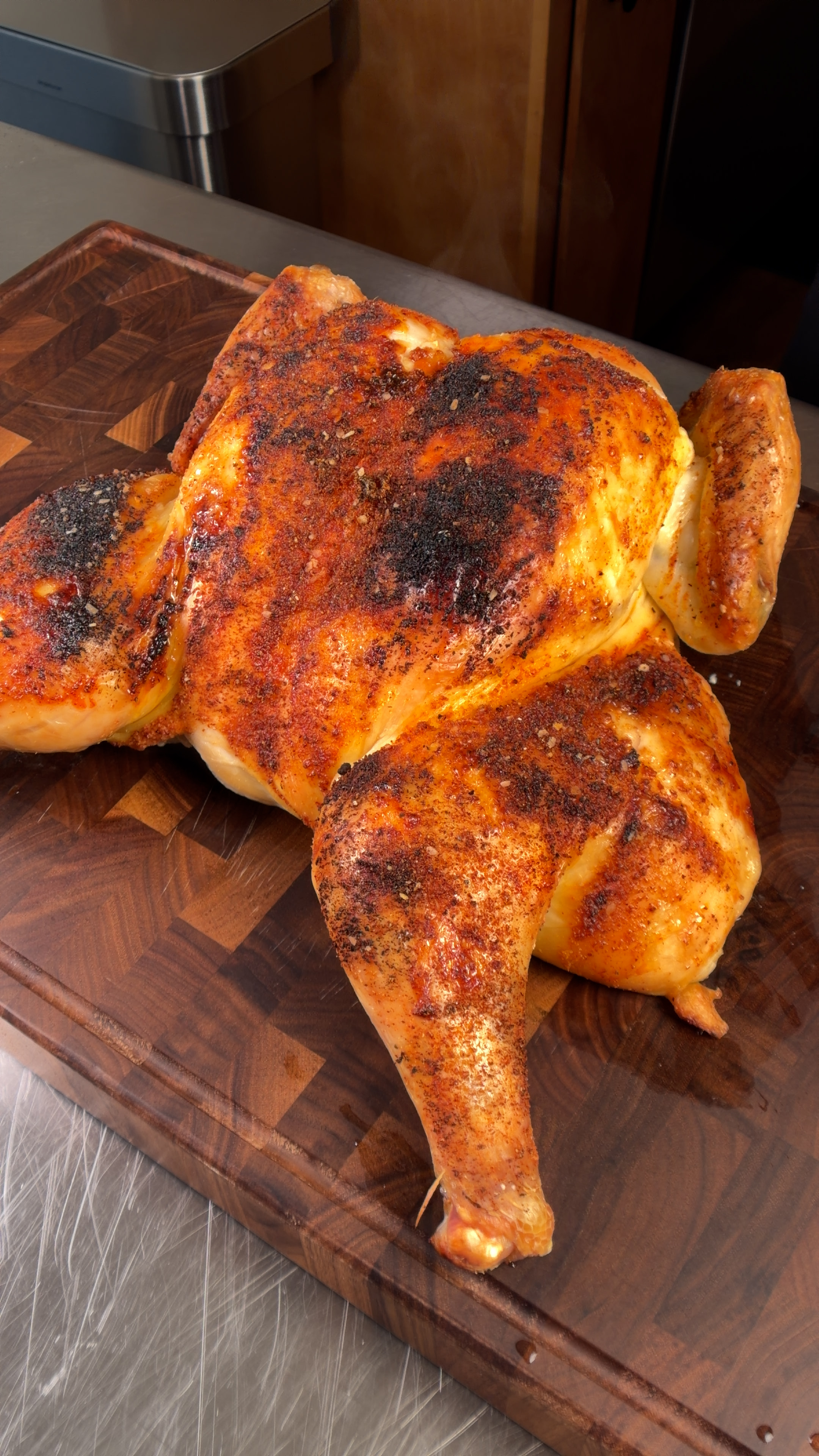 Roasted spatchcock chicken with crispy golden-brown skin on a cutting board