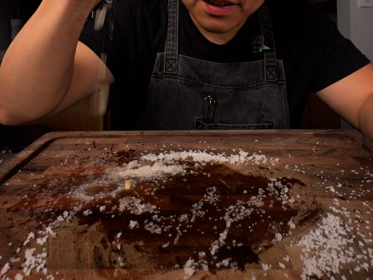 Chef holding a squeezed lemon over a salted cutting board