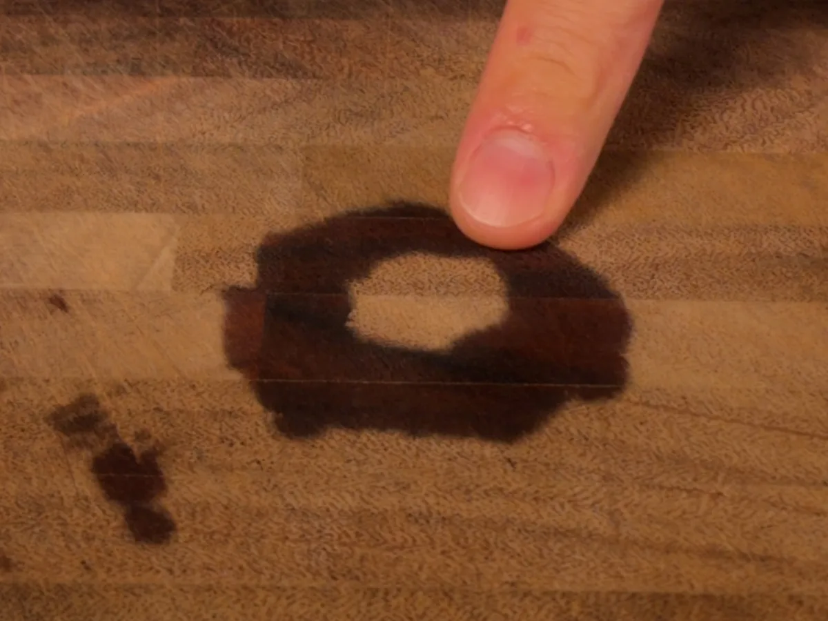 A dark ring stain soaked into a wooden board