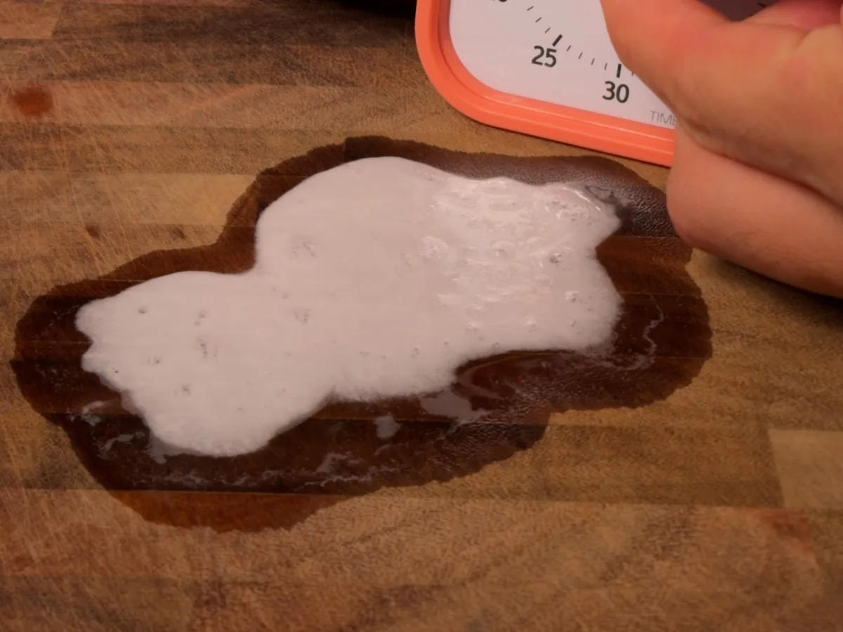 A timer over a foaming reaction on a wooden board