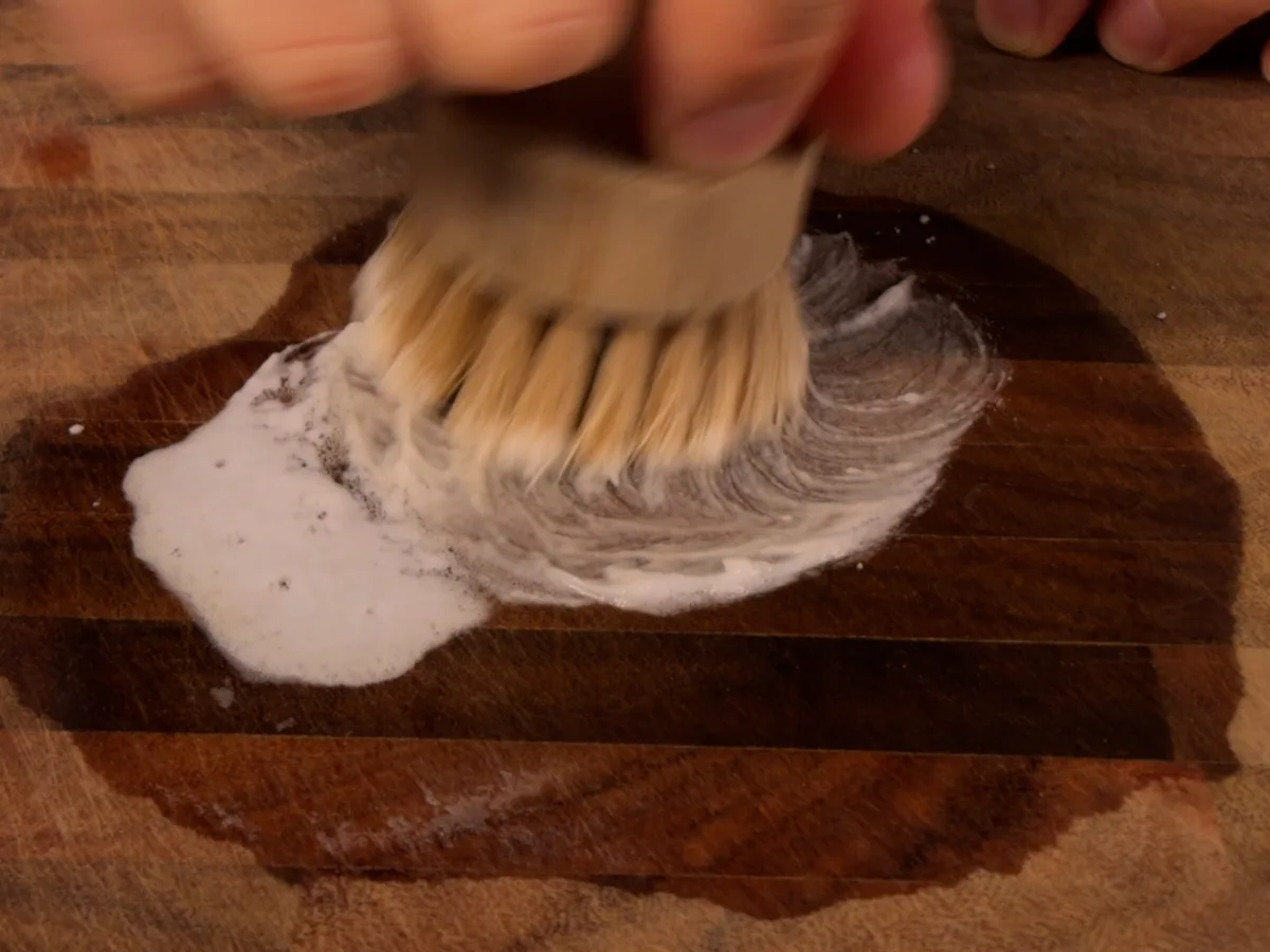 Scrubbing a wooden board with a dish brush