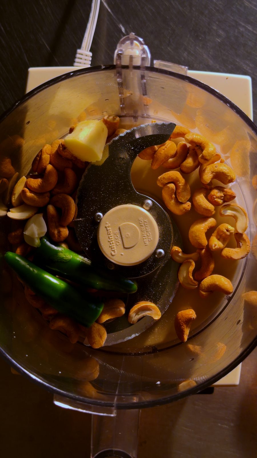 Cashews, ginger, garlic, and green chilies in a food processor bowl