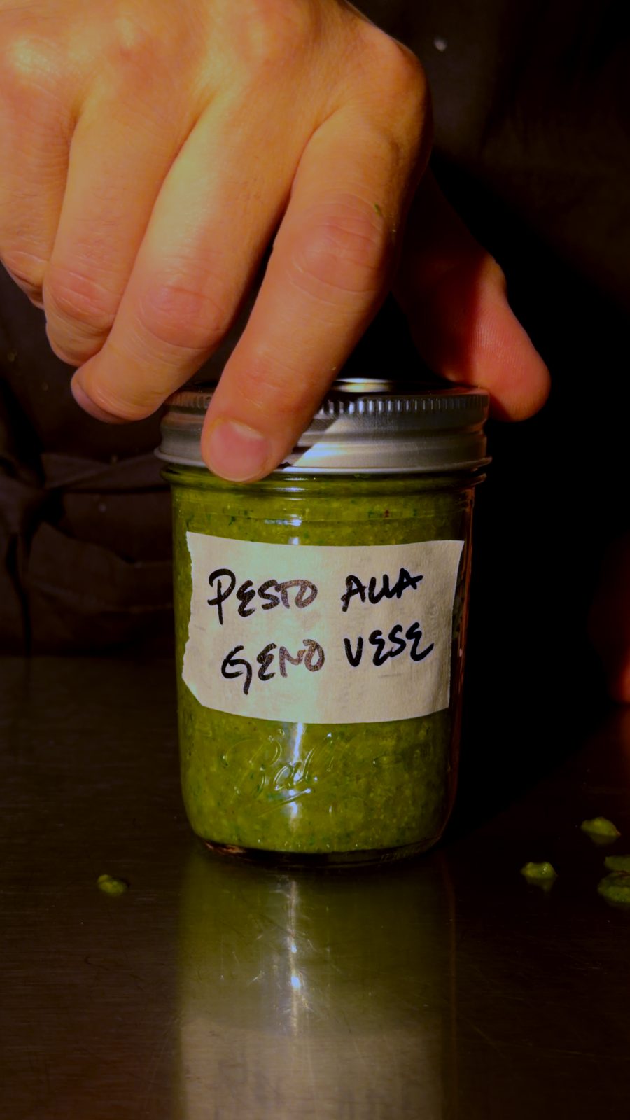 A jar of bright green pesto alla Genovese with a handwritten label