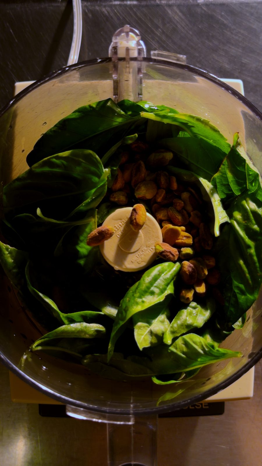 Basil and toasted pistachios in a food processor bowl