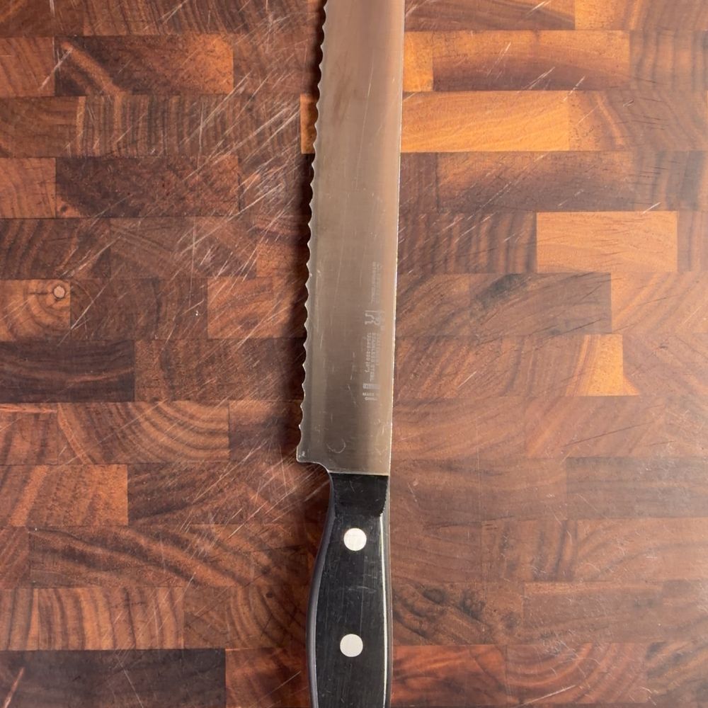 A serrated bread knife on a wood cutting board