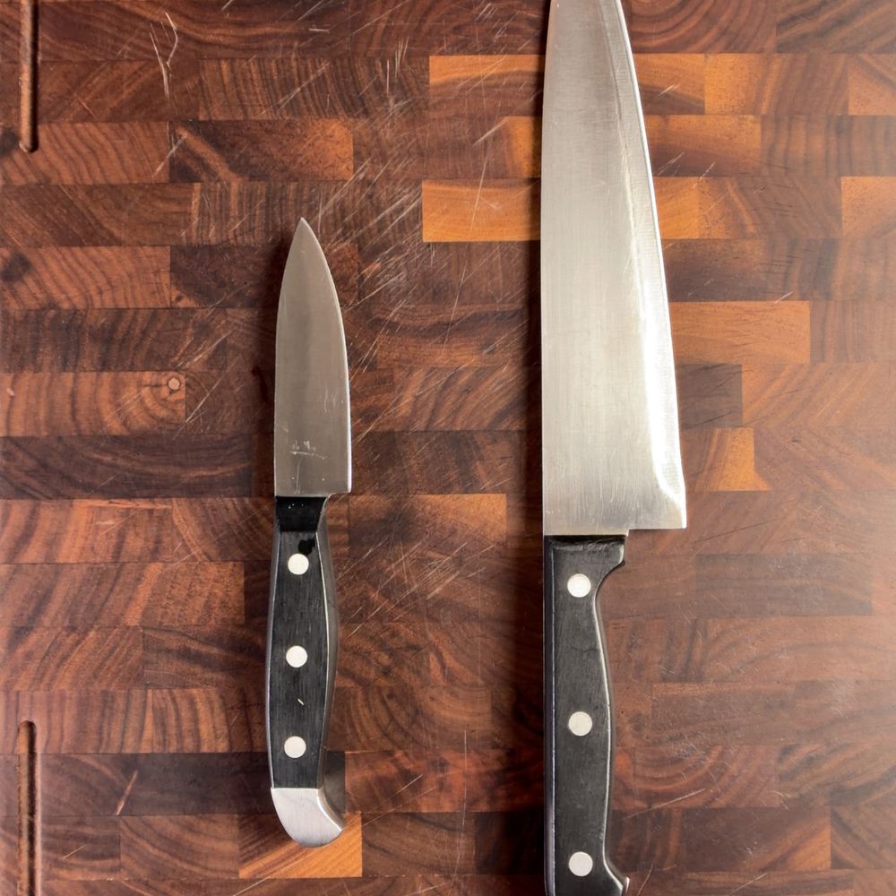 A soft-steel chef knife and paring knife side by side on a wood board