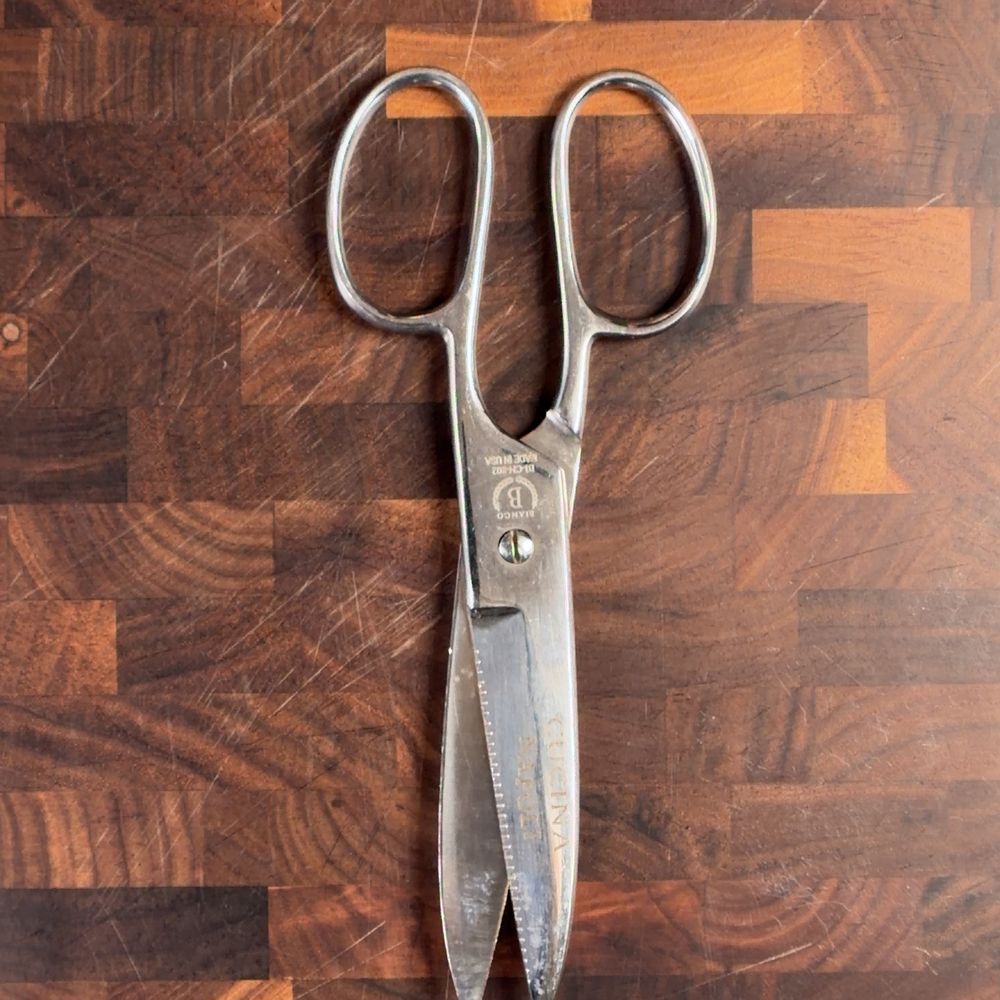All stainless steel kitchen shears on a wood cutting board