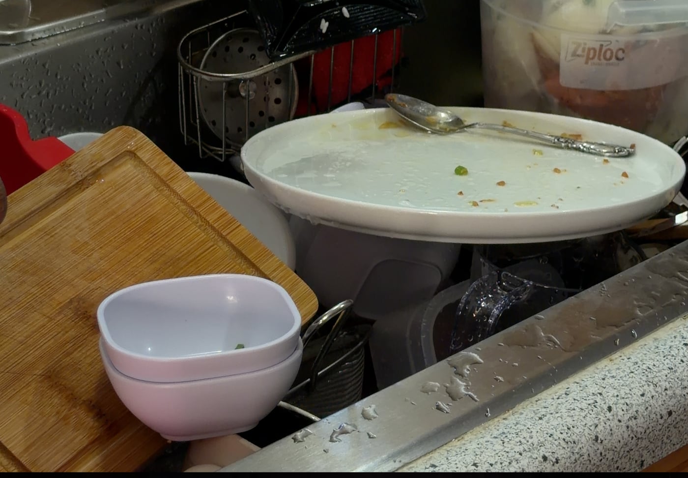 Dirty dishes piled in a kitchen sink with food residue, a fruit fly breeding ground