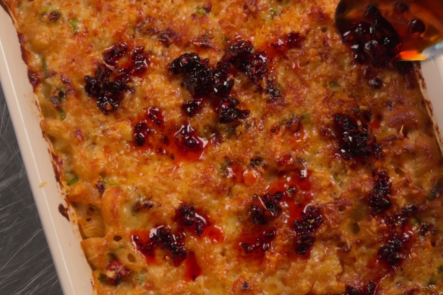 Overhead of the chili crisp mac with chili crisp oil drizzled over a golden crust.
