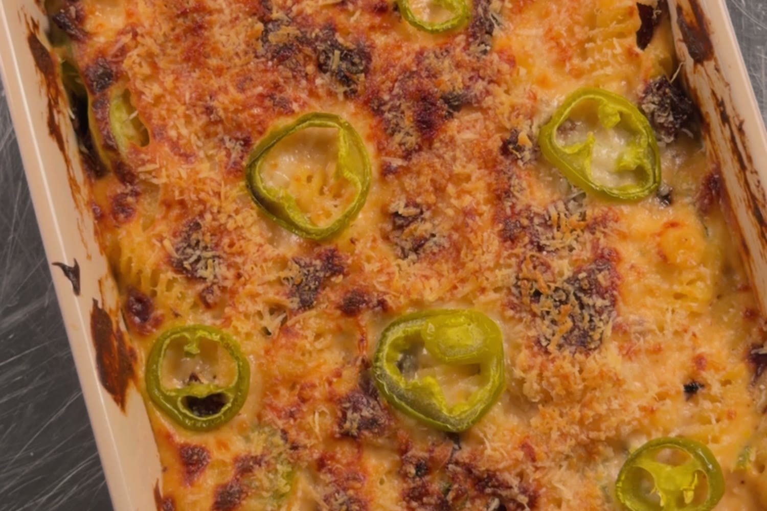 Overhead of the jalapeno popper mac with pickled jalapeno slices on a golden crust.