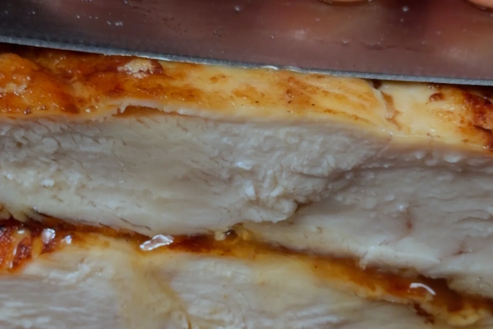 A seared chicken breast sliced open, showing a juicy, moist interior
