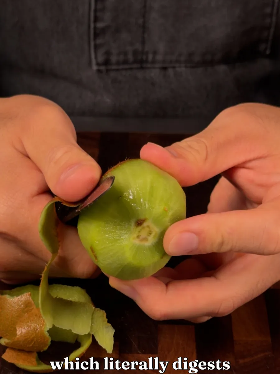 A kiwi being peeled on a cutting board