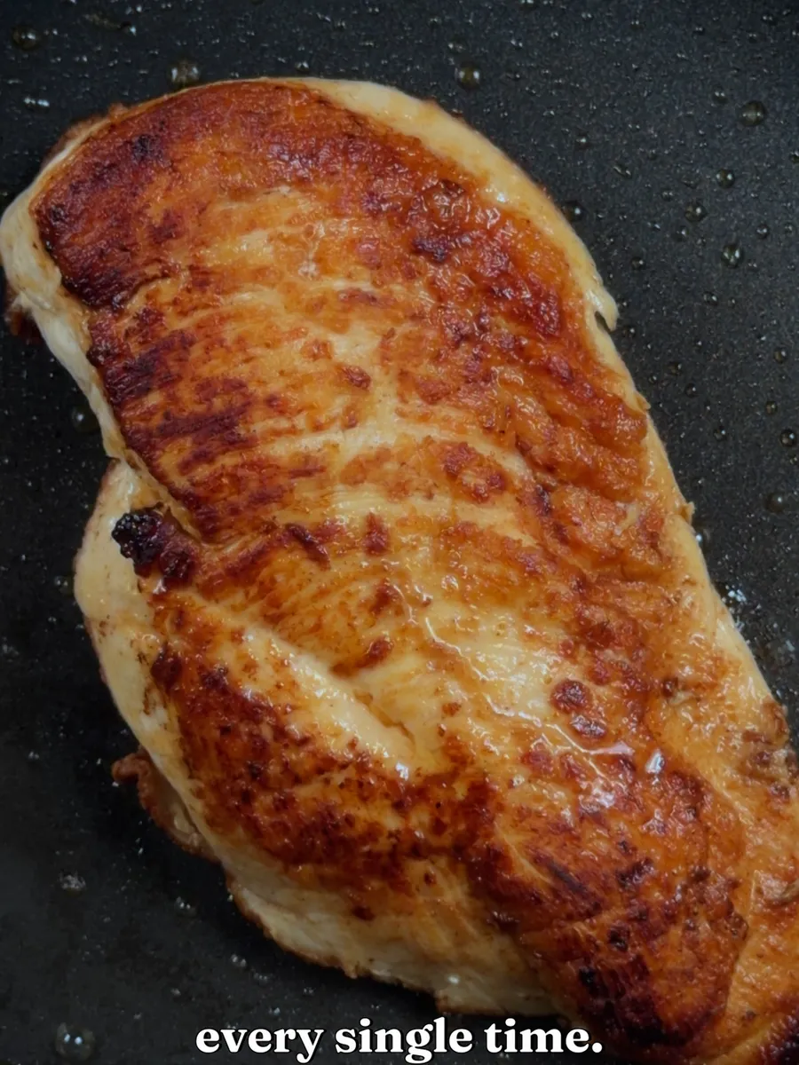 A golden-brown seared chicken breast in a pan