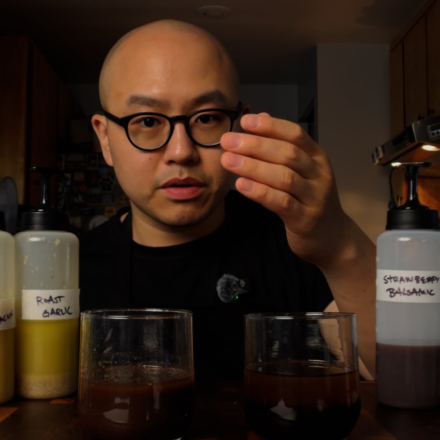 Chef Fatty between two glasses of vinaigrette with labeled squeeze bottles of roast garlic and strawberry balsamic dressings