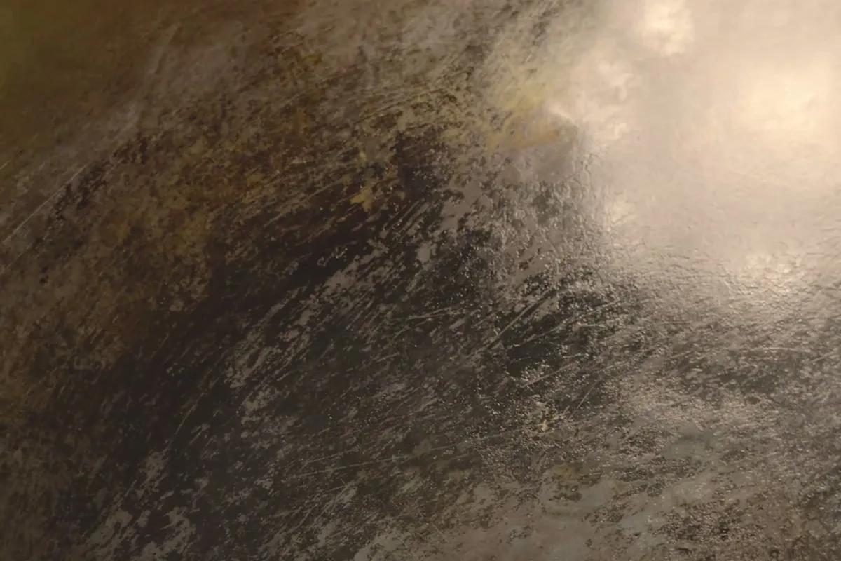 A carbon steel wok surface with a mottled bronze and black seasoned patina from months of use