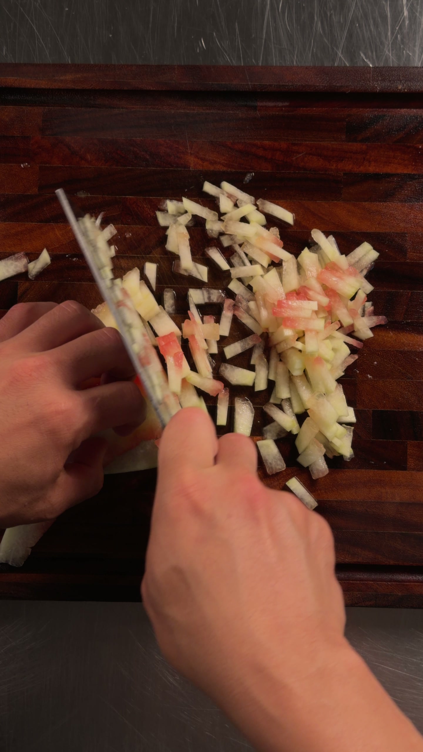 Dicing the pale watermelon rind small.