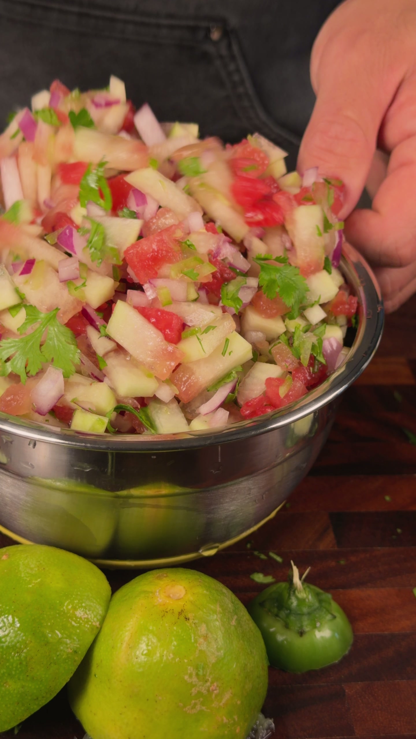 A steel bowl of watermelon rind pico de gallo with tomato, red onion, and cilantro.