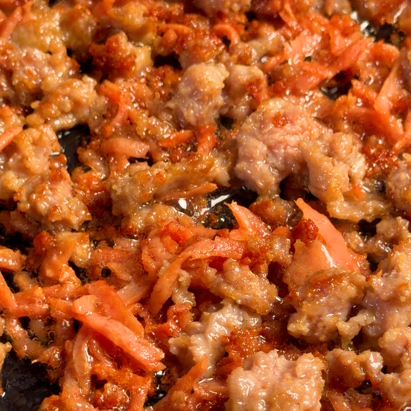 Crispy crumbled Spam and ground pork browned dark in a hot enameled cast iron pan