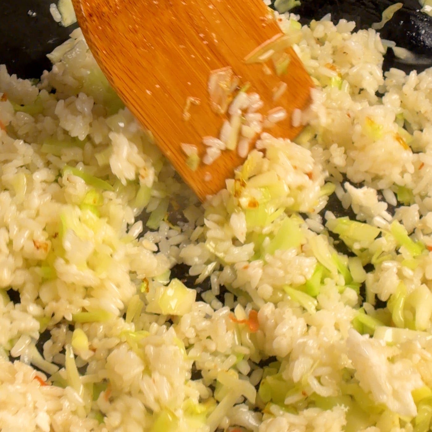 Day-old jasmine rice tossed with chopped cabbage and green onions in a thin enameled cast iron pan