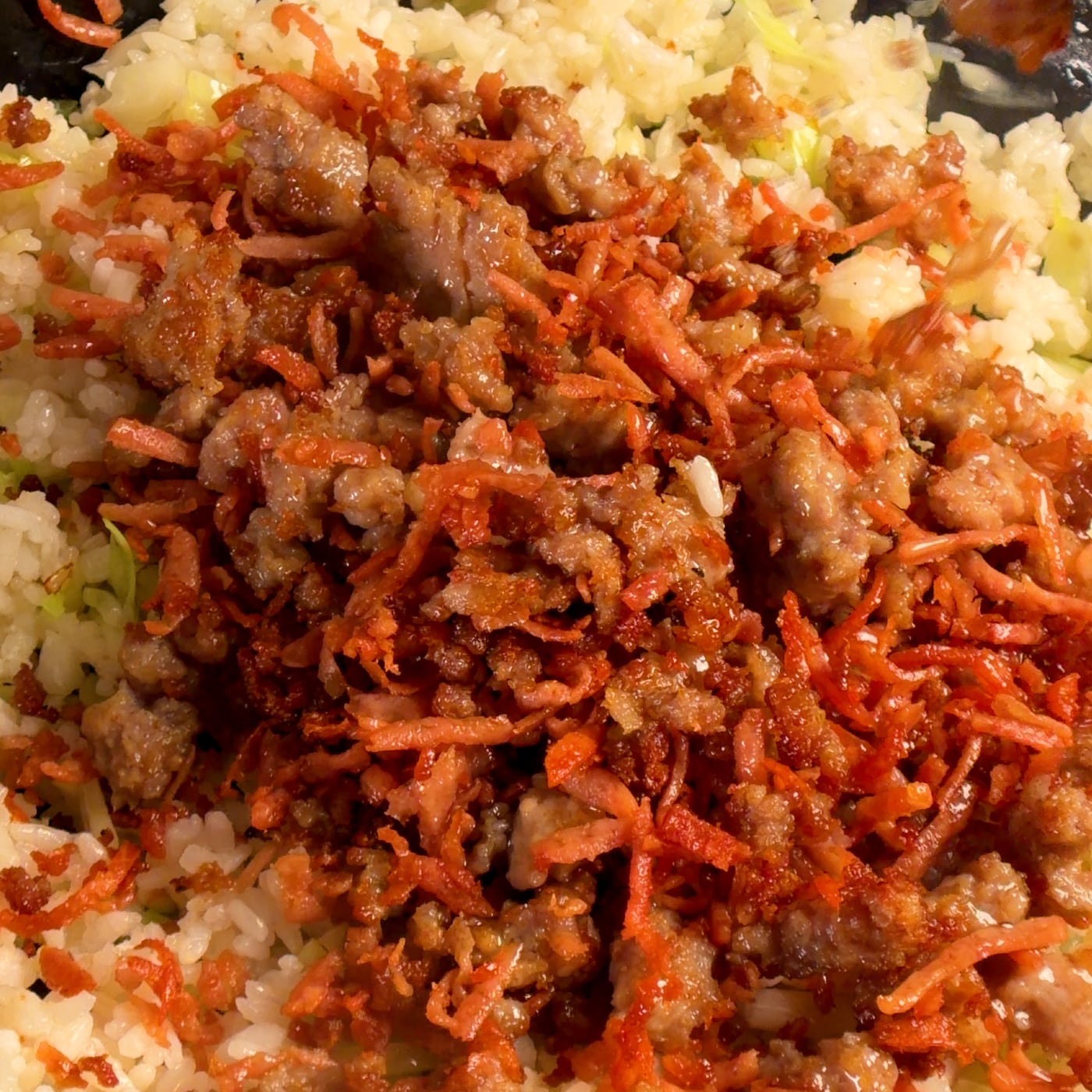 Crispy ground pork and shredded spam being folded back into the fried rice