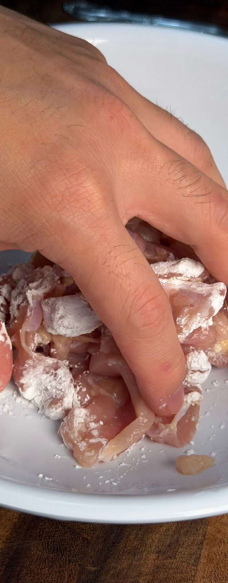 Tossing chicken with cornstarch until fully coated